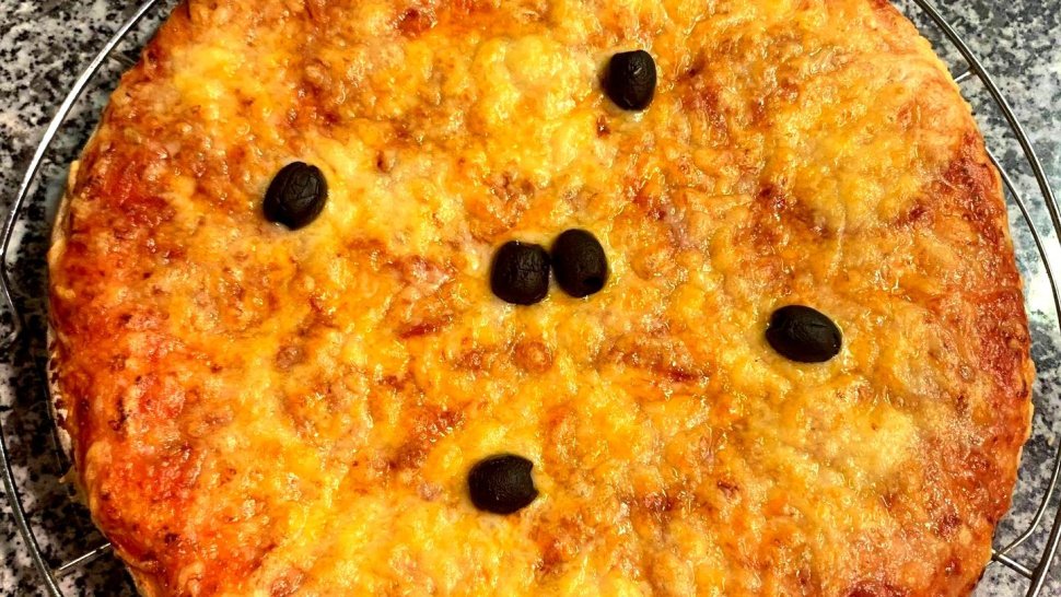 Pizza au fromage doré avec olives noires sur une grille de granit